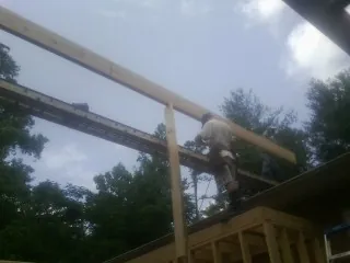 Carpenter setting a ridge beam over a new addition frame — Ice Dam Removal by Roofing Brothers in Fairhaven