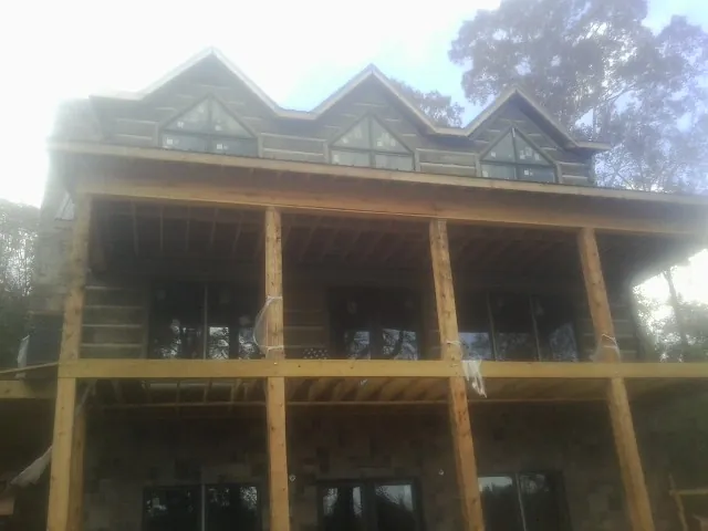 Dormers and porch framing on a large log home under construction — Roof Coating work by our crew in Fairhaven