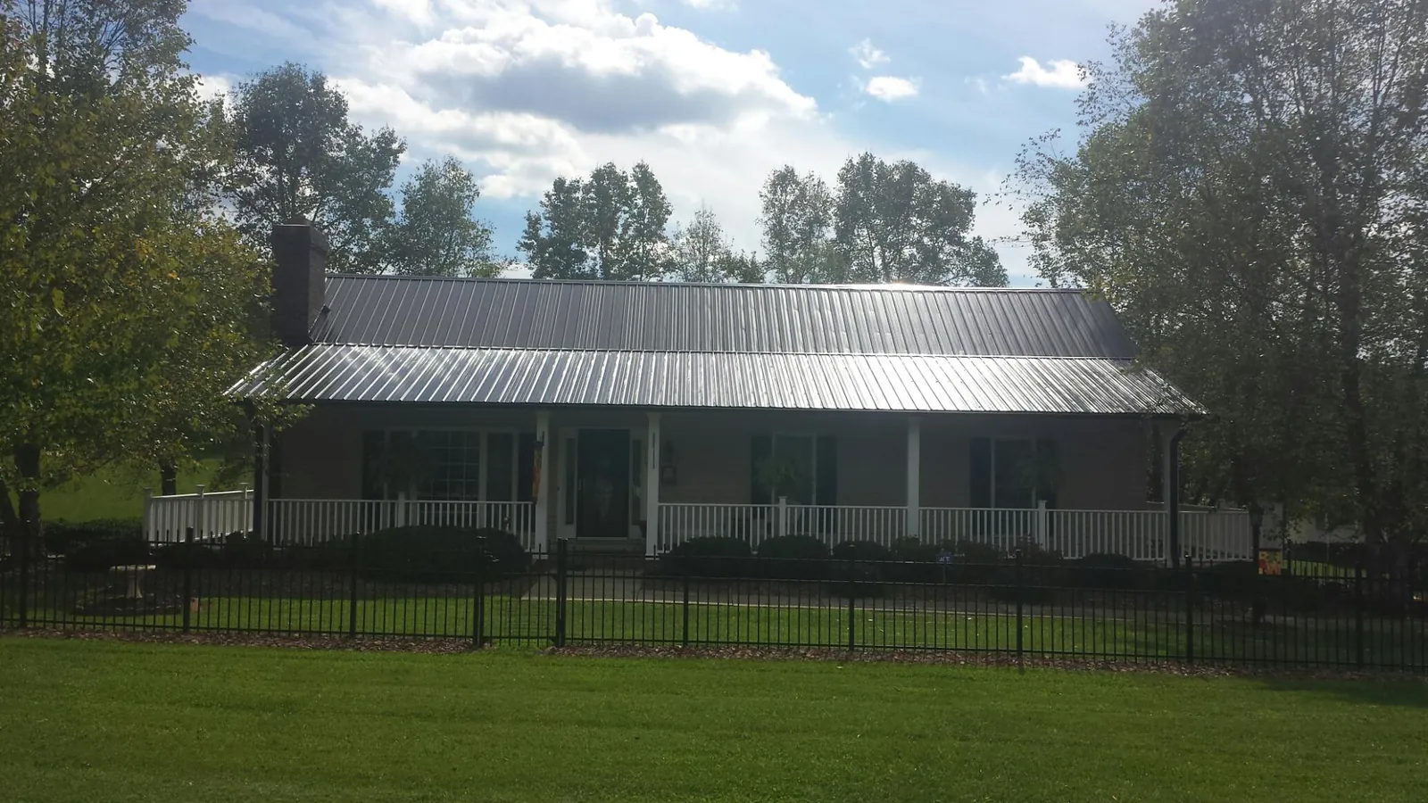 Gray metal roof on a brick ranch with a full width front porch — Gutter Guard Installation work by our crew in Fairhaven