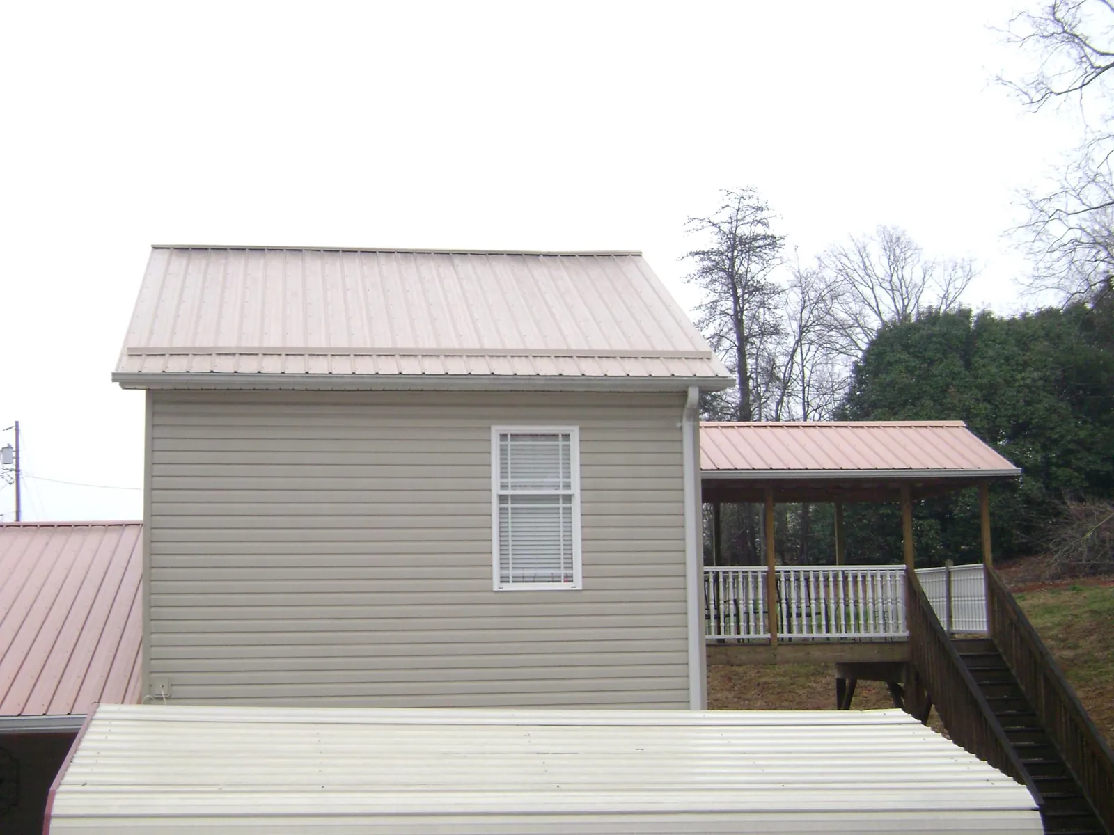 Tan metal roofs on a two story addition and attached porch, from a Roof Replacement job in Fairhaven