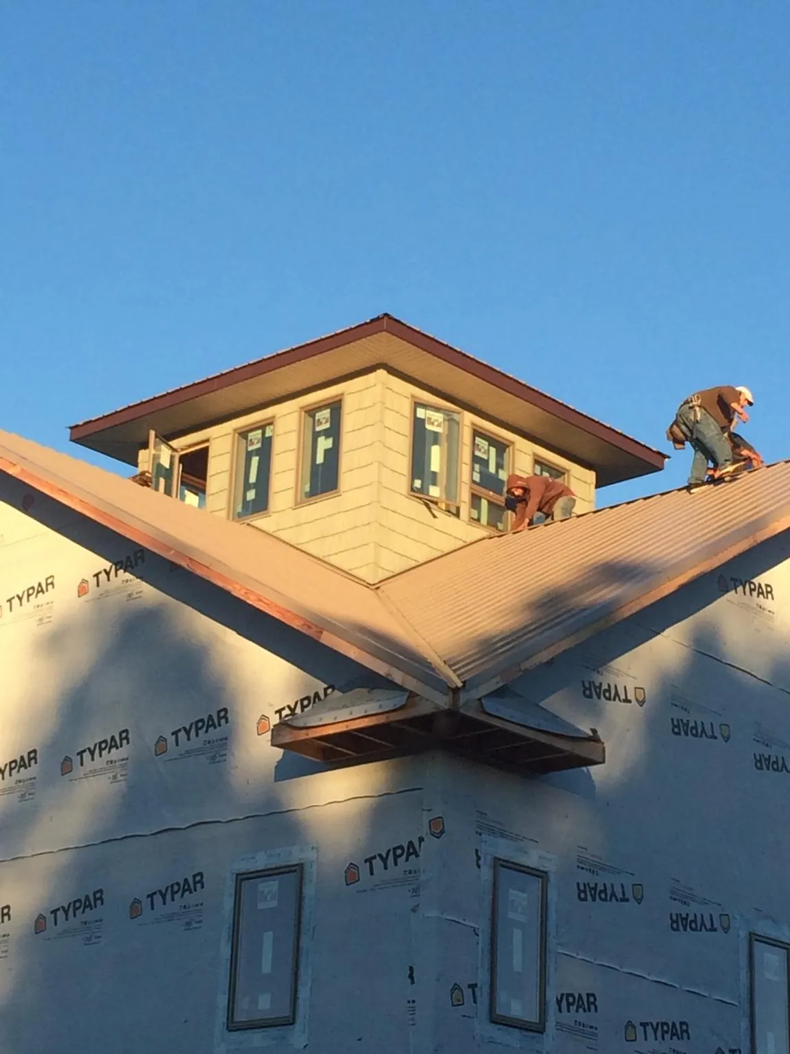 Roofers working around a rooftop cupola on a new metal roof at sunset — Roof Waterproofing in Fairhaven by Roofing Brothers
